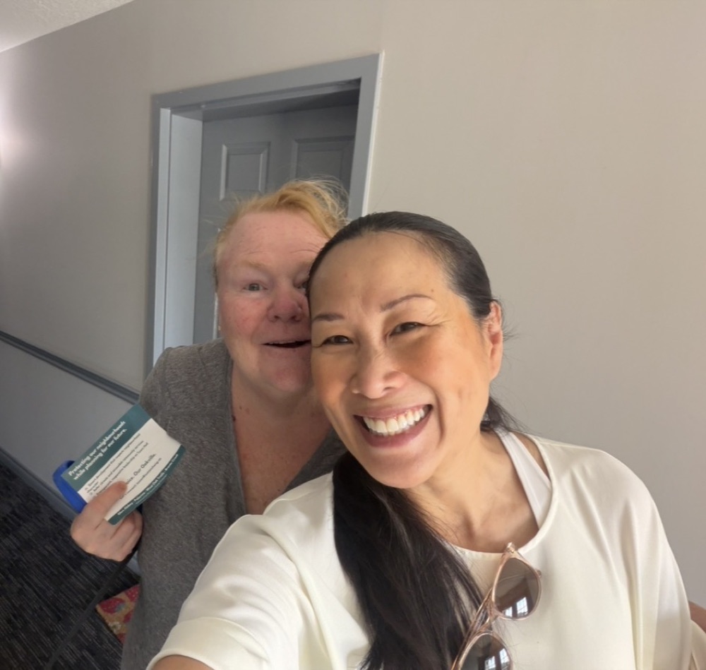 Suzan Chong taking a selfie with a smiling woman who is holding a campaign card
